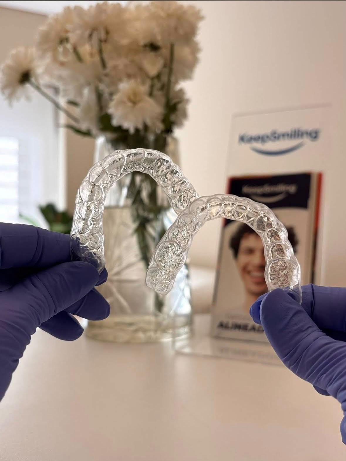 Dos alineadores transparentes sostenidos con guantes clínicos